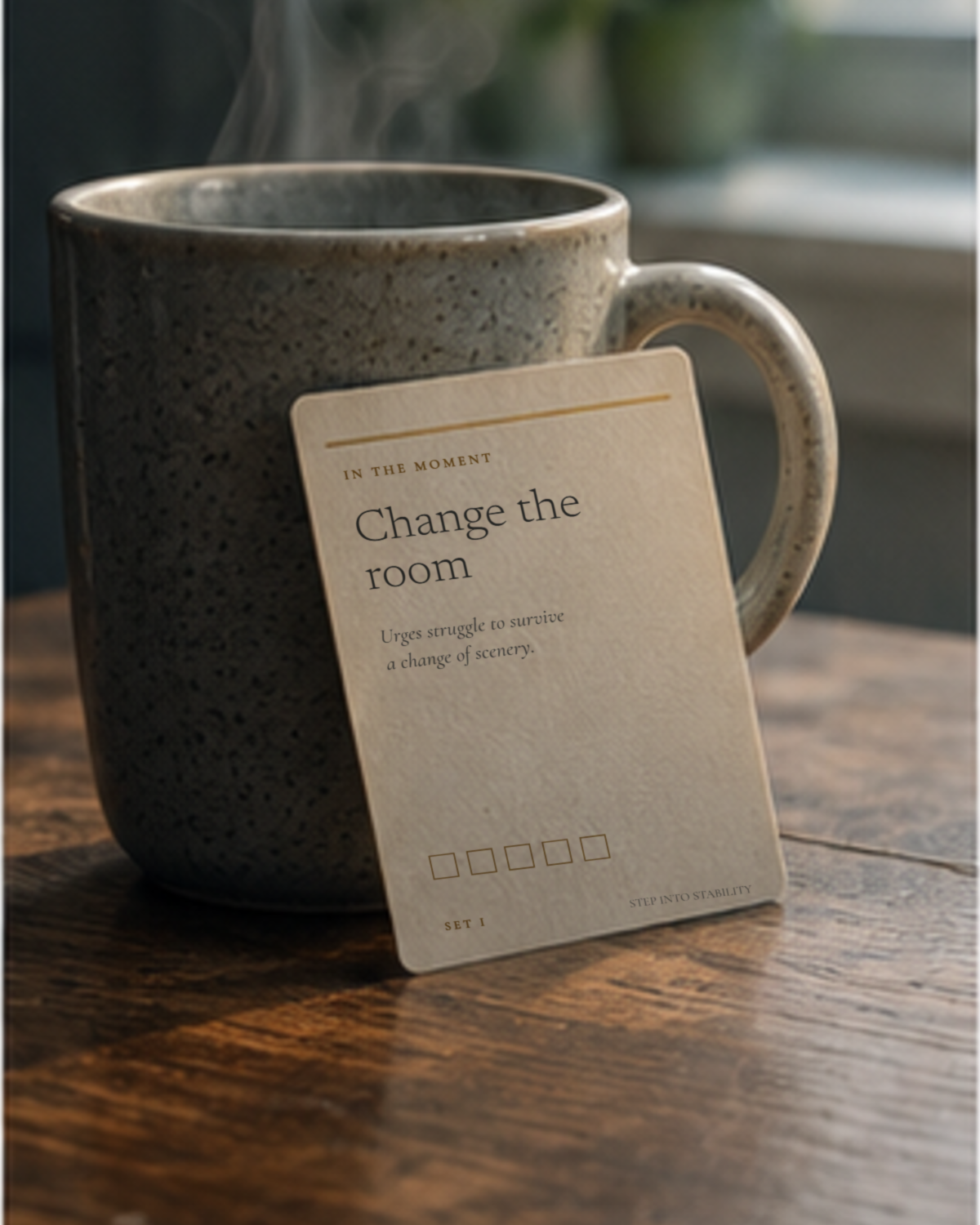 A pocket card reading Change the room propped against a mug of tea in morning light