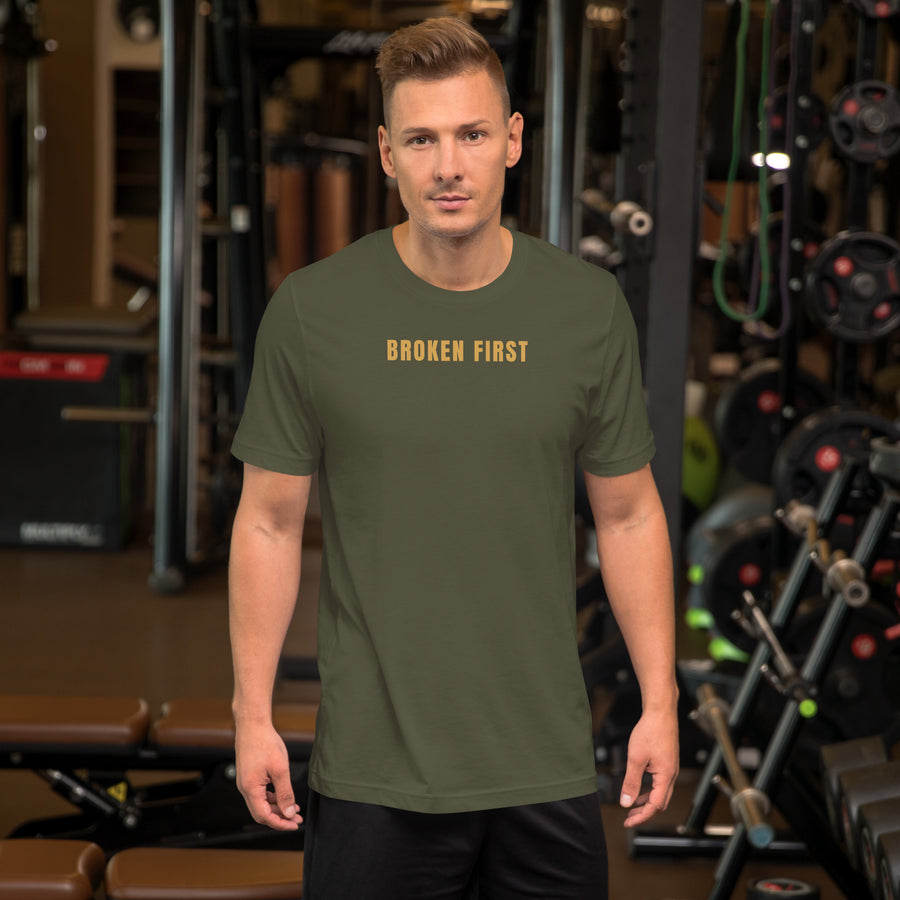 Built Different T-shirt worn by a man in a gym, Military Green, gold BROKEN FIRST across the chest